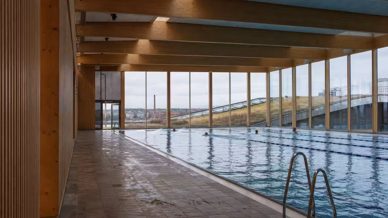 Vue intérieure d’un grand centre aquatique en bois avec bassin de nage, vitrages et charpente apparente