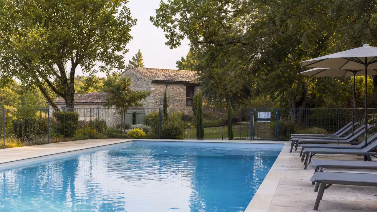 Bassin extérieur sécurisé d’un hébergement touristique avec transats, terrasse et végétation méditerranéenne