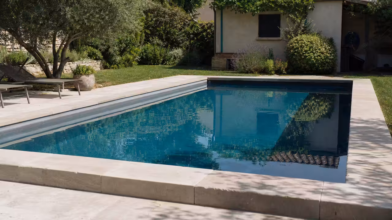 Piscine rectangulaire enterrée dans un jardin, avec plans de construction et documents administratifs sur une table