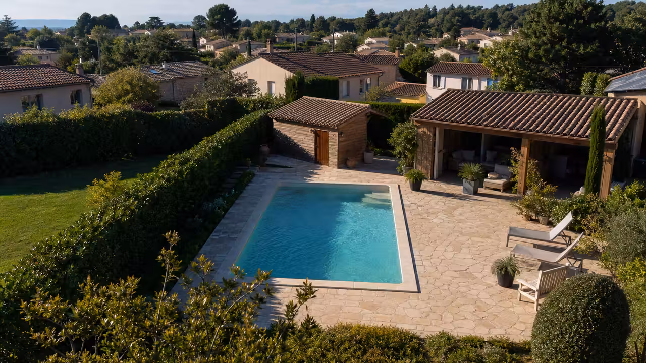 Vue aérienne oblique d’un jardin résidentiel avec piscine fixe, abri de jardin et pergola ouverte