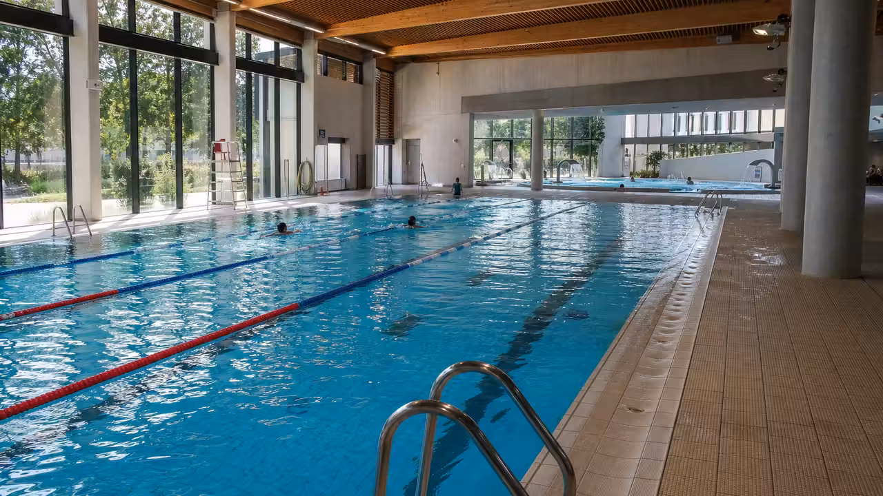 Intérieur lumineux d’un centre aquatique moderne avec bassin de nage et zone de loisirs aquatiques séparée