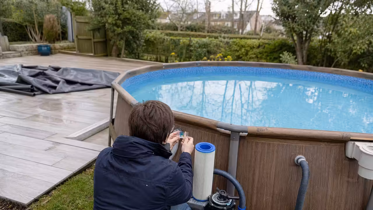 Propriétaire contrôlant le filtre et la qualité de l’eau d’une piscine hors-sol au printemps