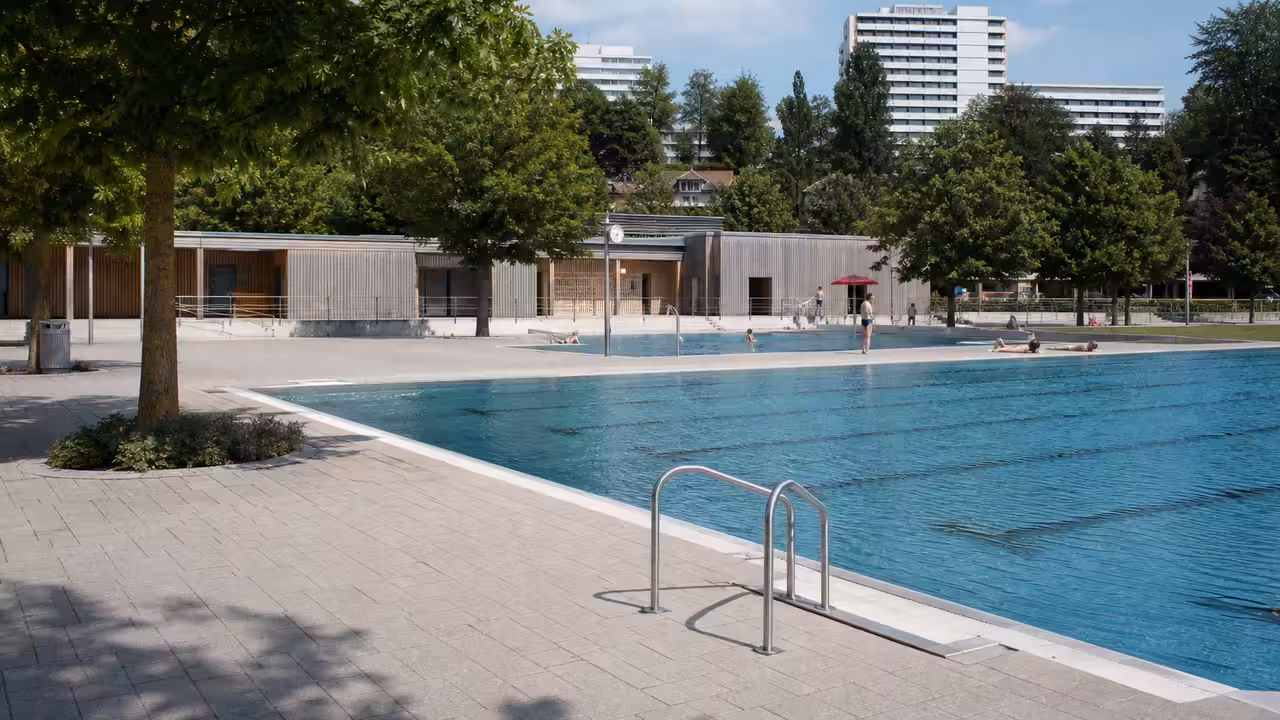 Vue d’un bassin municipal extérieur moderne entouré de plages végétalisées et de zones ombragées