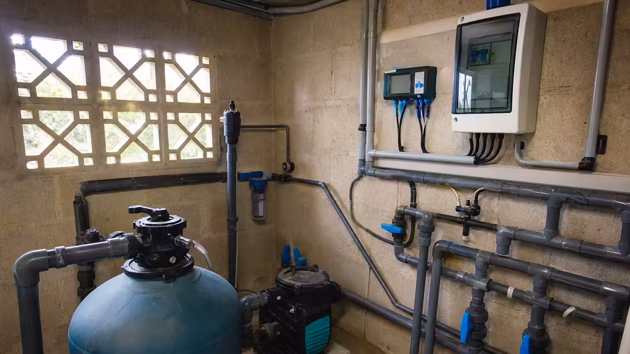 Local technique de piscine organisé avec pompe, filtre à sable, vannes PVC et coffret électrique mural