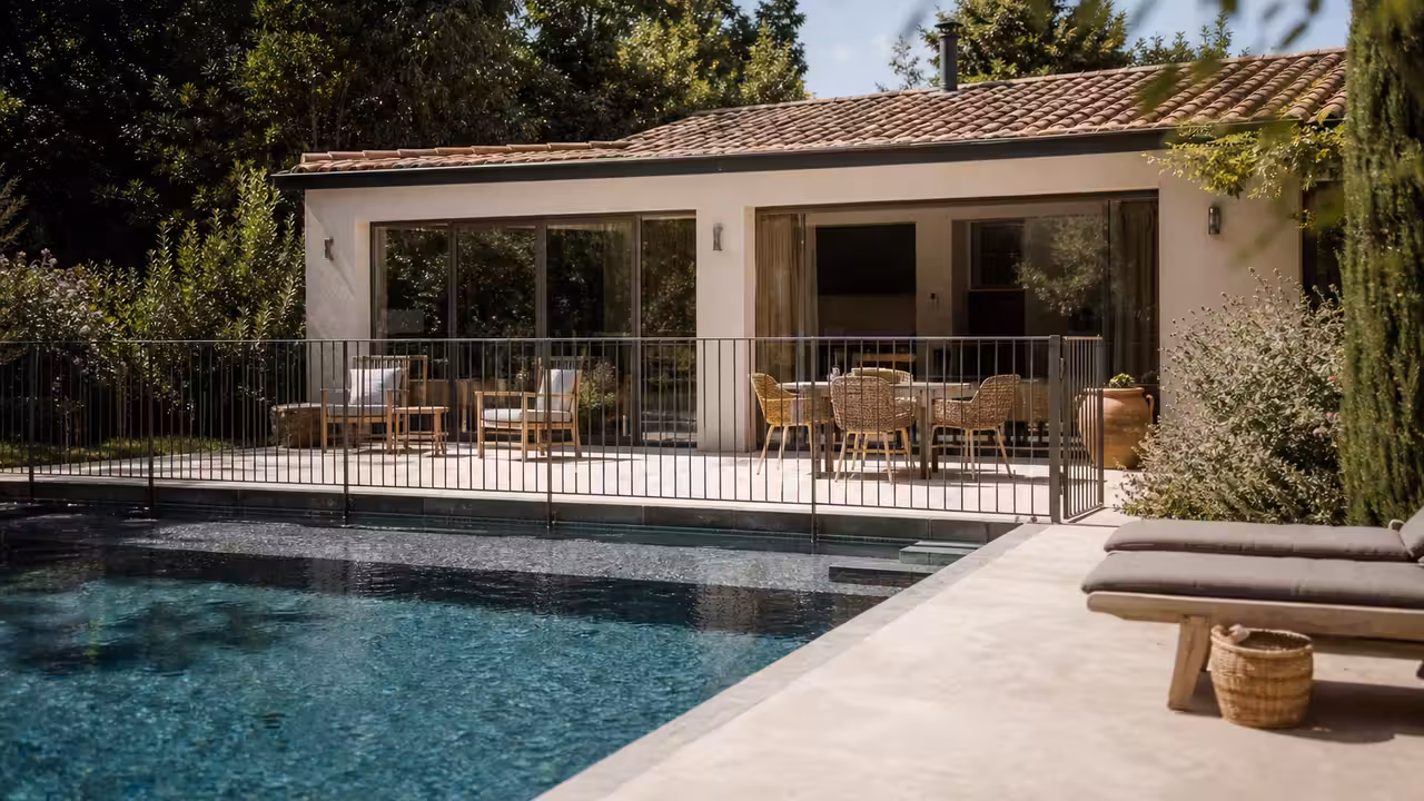 Petit pool house lumineux au fond d’un jardin, avec terrasse en bois et piscine sécurisée à proximité