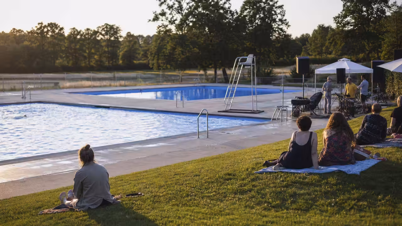 Bassin extérieur municipal bordé d’une pelouse, préparé pour une animation en fin de journée estivale