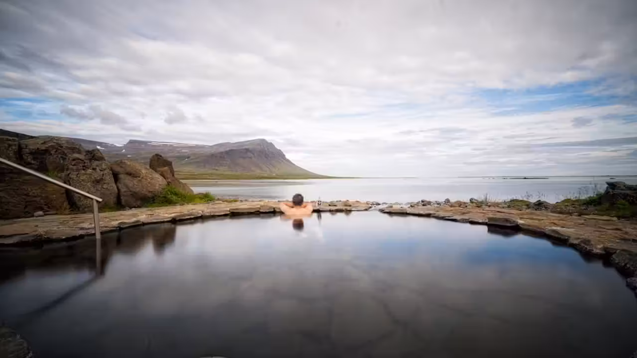 Bassin extérieur chauffé en Islande avec vapeur, nageurs lointains et paysages volcaniques en hiver