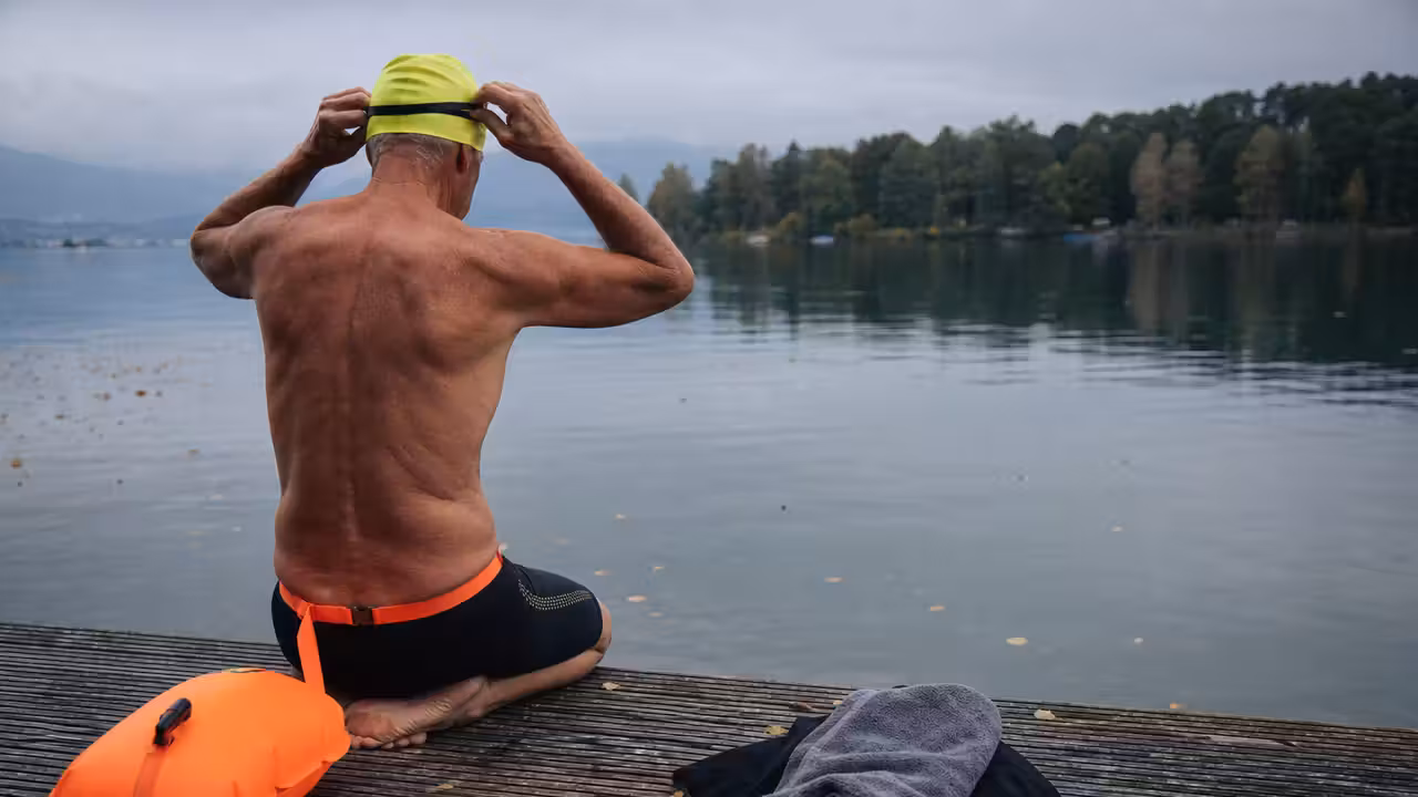 Nageur senior équipé d’un bonnet et d’une bouée de sécurité avant une baignade en eau froide