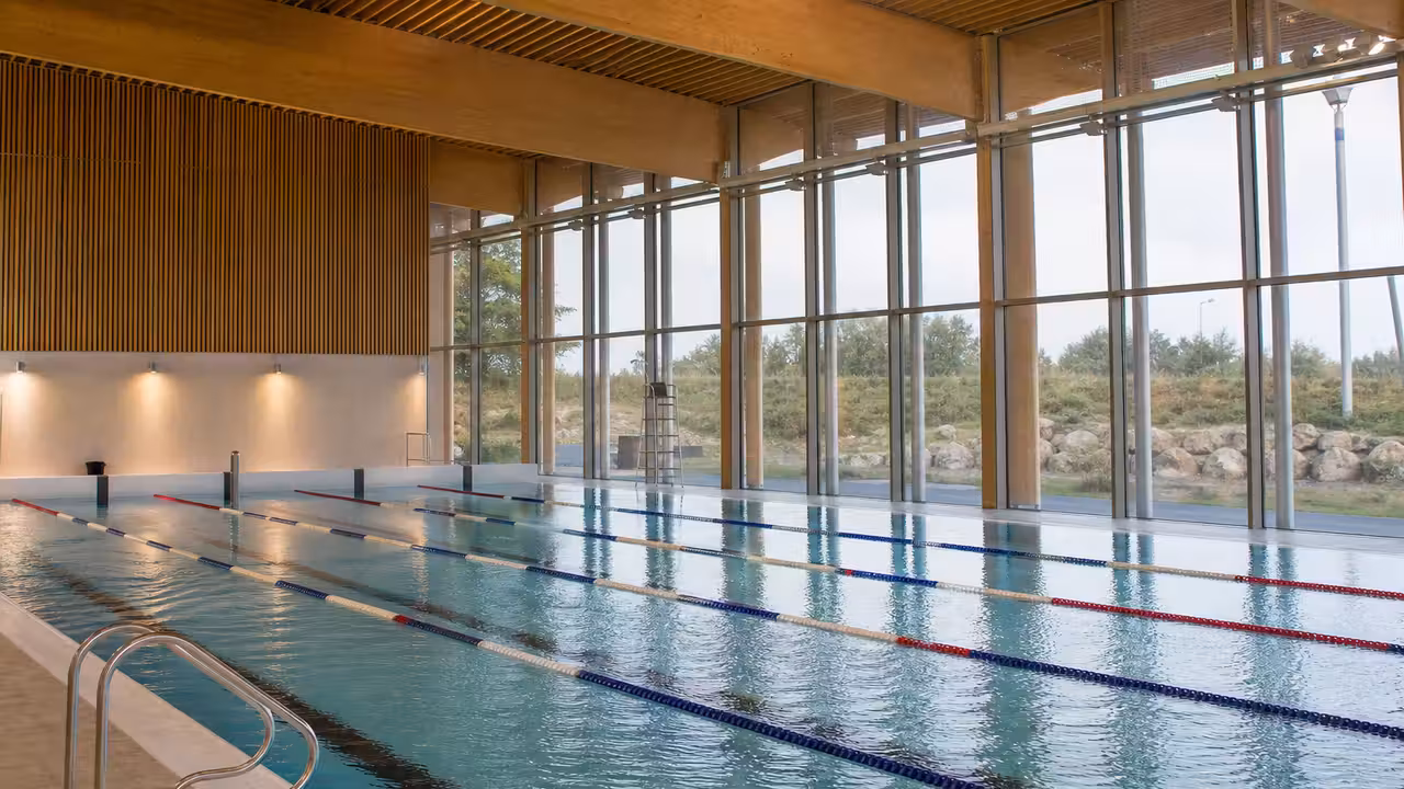 Bassin nordique extérieur de 50 mètres d’un centre aquatique moderne, avec lignes d’eau et bâtiment vitré