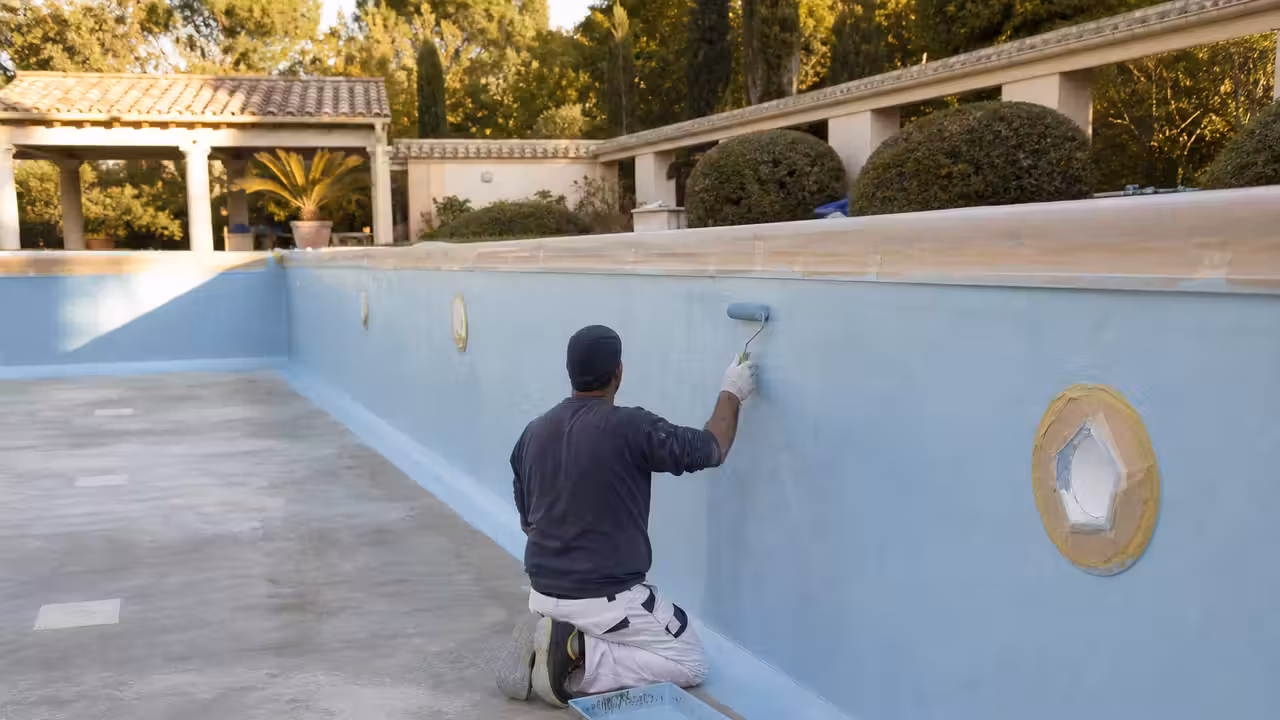 Bassin en béton vidé pendant une rénovation, avec parois préparées avant l’application d’une peinture piscine