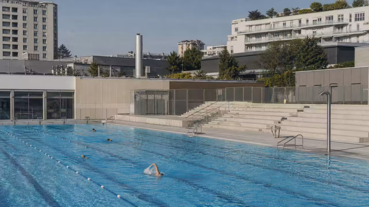 Vue en plongée d’un bassin public extérieur rénové, avec lignes d’eau, gradins et équipements techniques