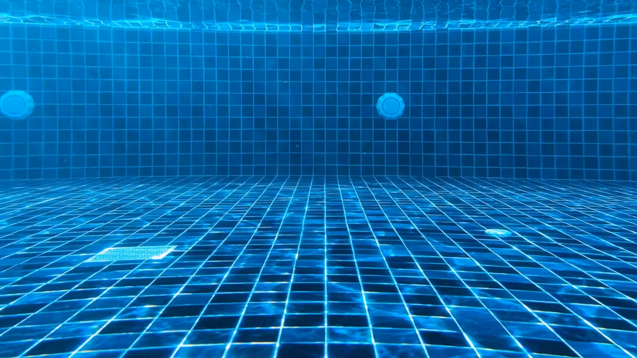 Bassin intérieur vide d’une piscine municipale ancienne, avec lignes d’eau et lumière naturelle latérale