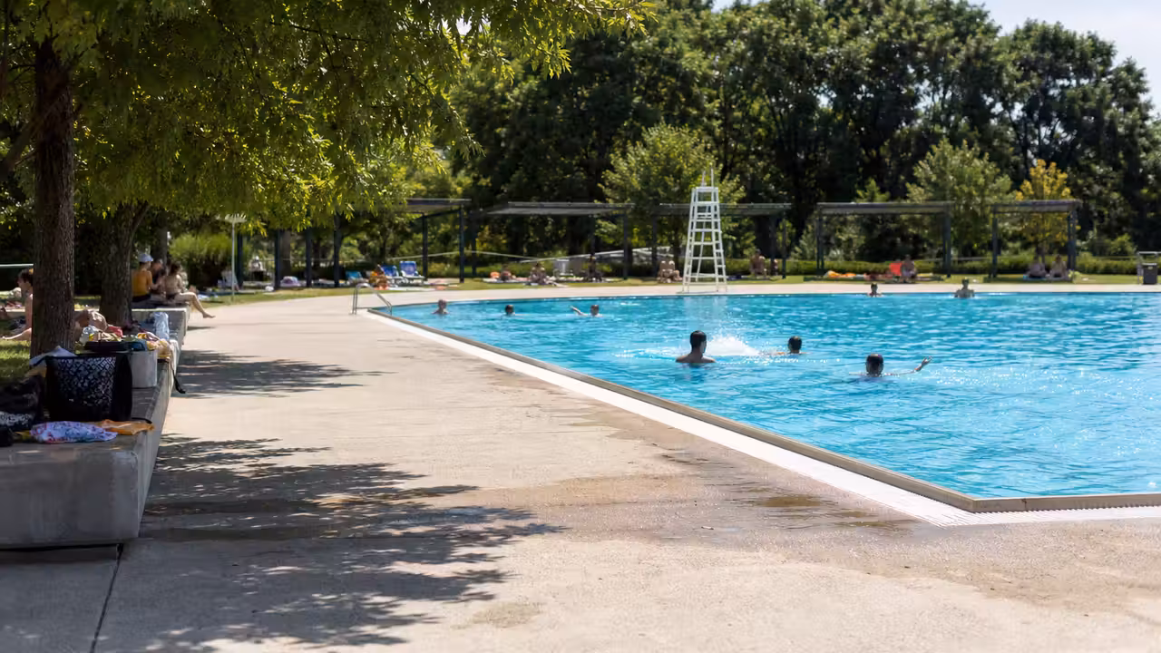 Baigneurs et nageurs dans une piscine publique extérieure lors d’une journée estivale ensoleillée
