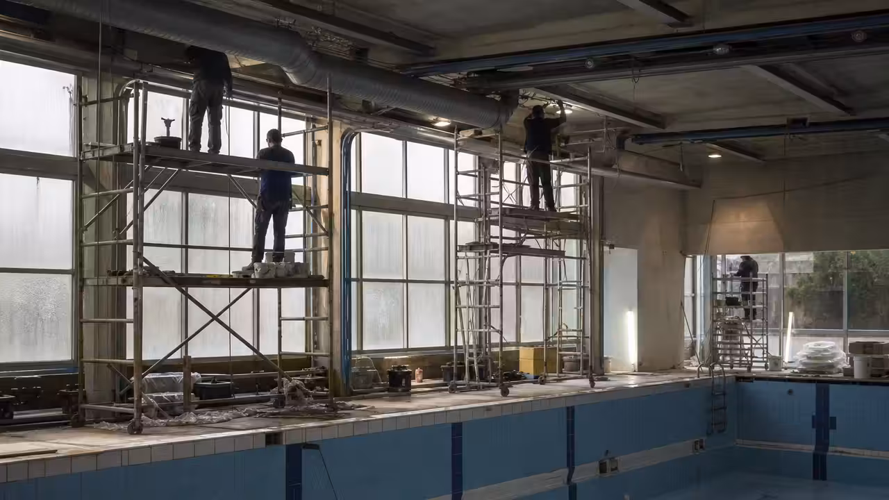 Bassin intérieur d’une piscine municipale vide pendant une rénovation des plafonds et équipements techniques