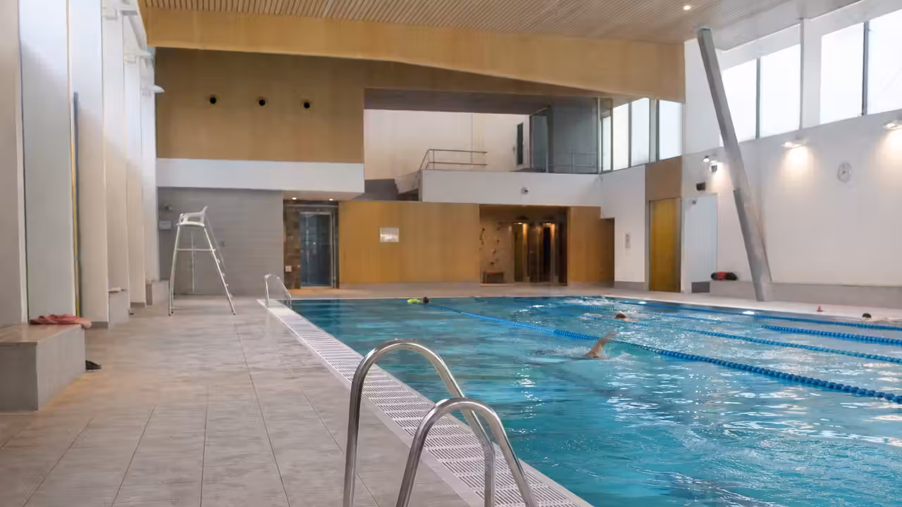 Intérieur lumineux d’une piscine municipale rénovée avec lignes d’eau, vestiaires et plages de bassin dégagées