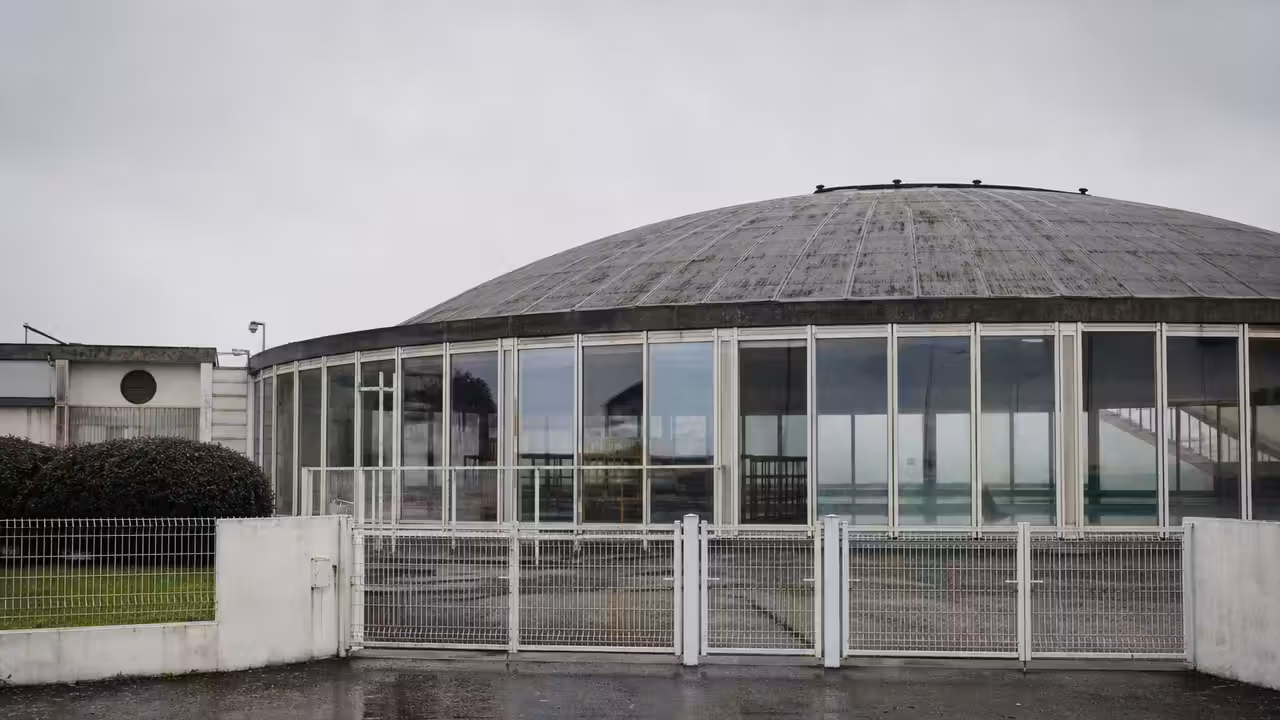 Entrée fermée d’une piscine publique des années 1970, avec coupole vitrée et bâtiment technique en arrière-plan
