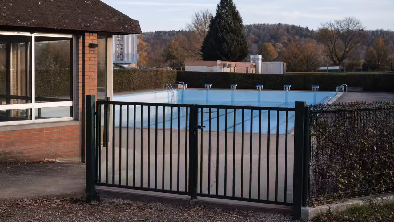 Bâtiment d’une piscine municipale française, bassin extérieur vide et équipements techniques en arrière-plan