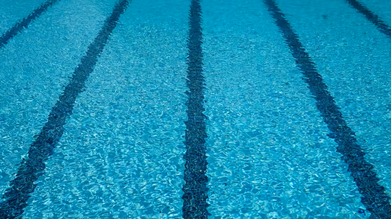 Bassin municipal vide avec lignes d’eau et gradins, illustrant la fermeture temporaire d’une piscine publique