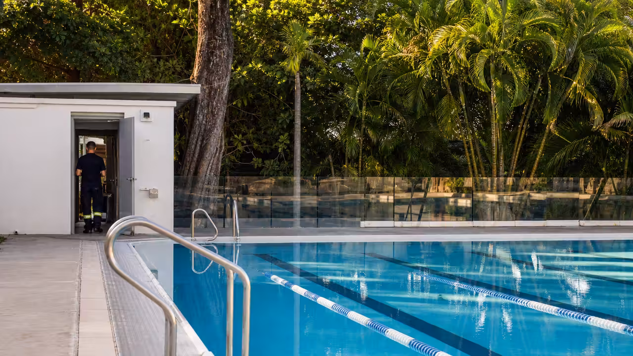 Bassin extérieur vide d’une piscine publique, avec lignes d’eau et local technique en arrière-plan