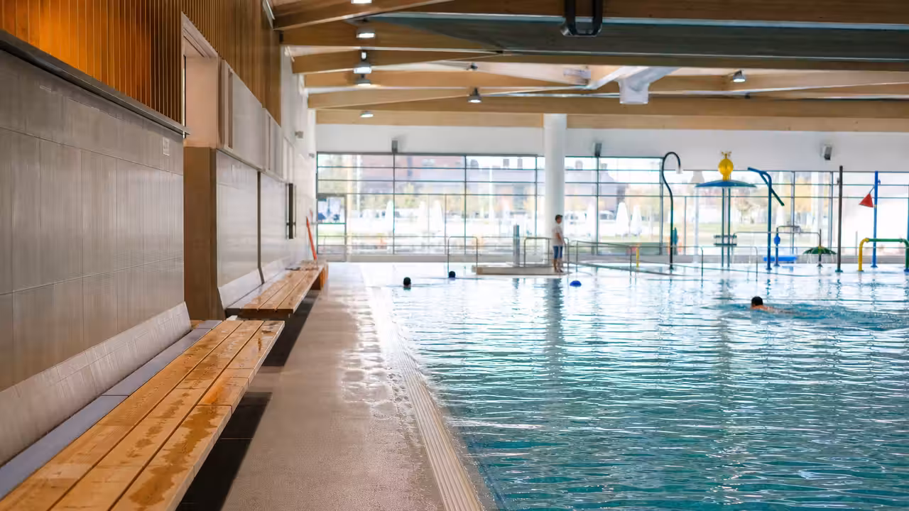 Bassin intérieur rénové avec bancs en bord de plage et espace ludique aquatique pour les familles