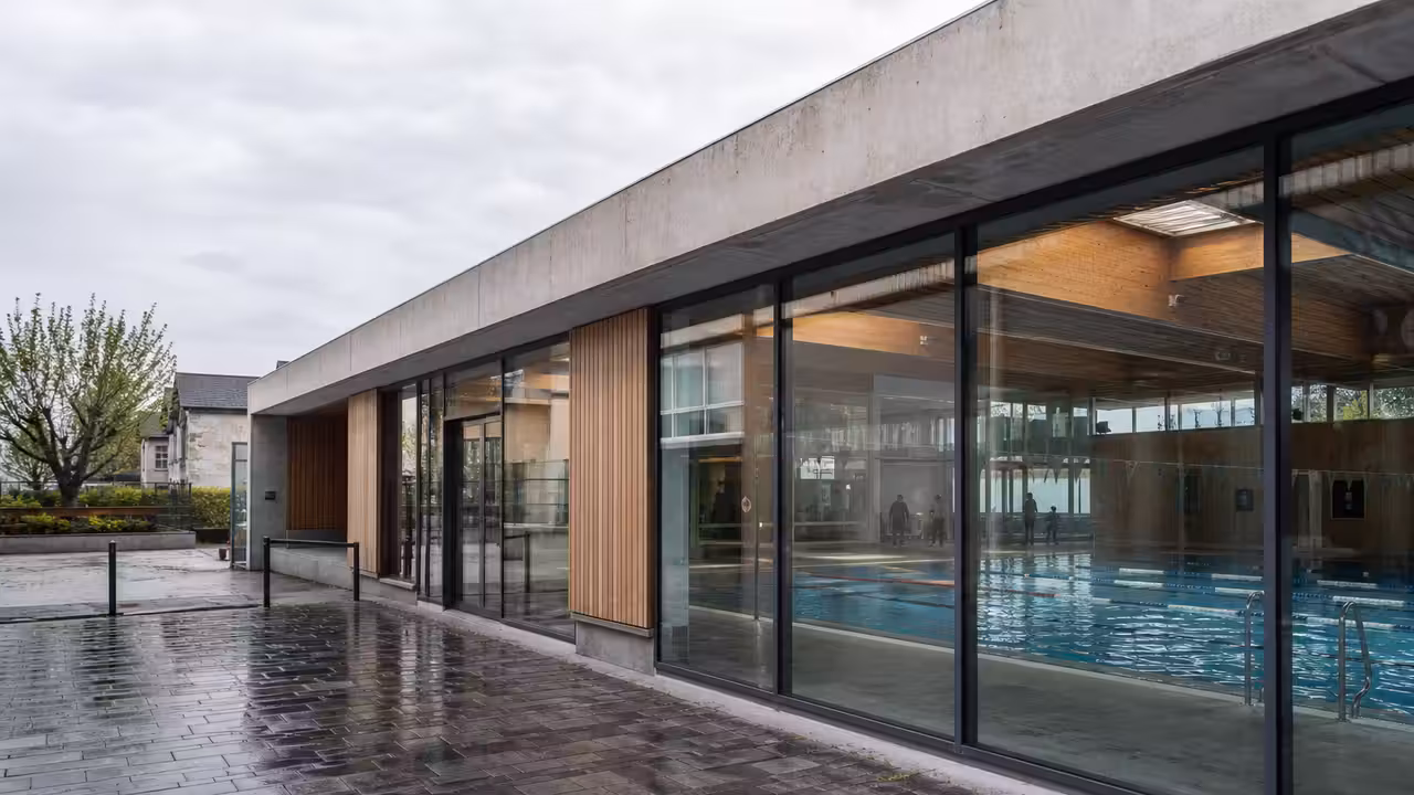 Bassin intérieur lumineux d’une piscine publique avec lignes d’eau, gradins et équipements techniques visibles