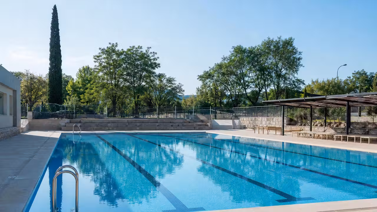 Bassin extérieur rénové avec plages minérales, lignes d’eau et espaces de détente sous le soleil d’été