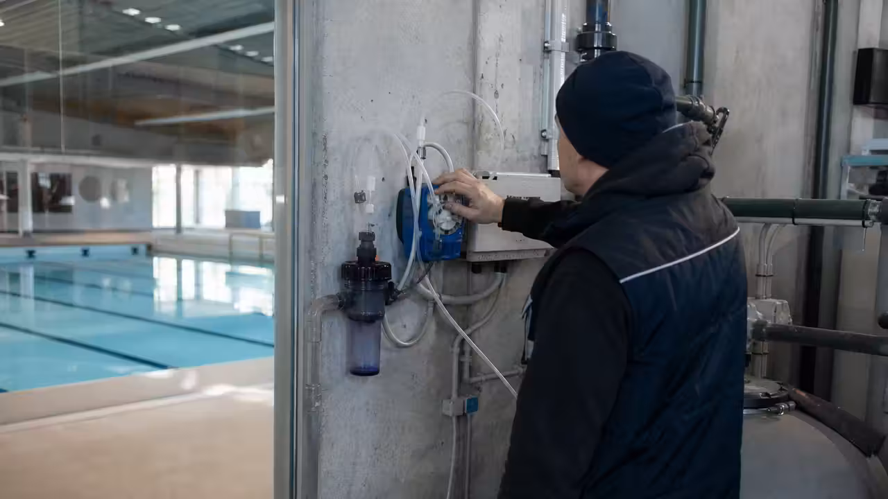 Technicien contrôlant le système de dosage et de filtration d’une piscine publique avant réouverture