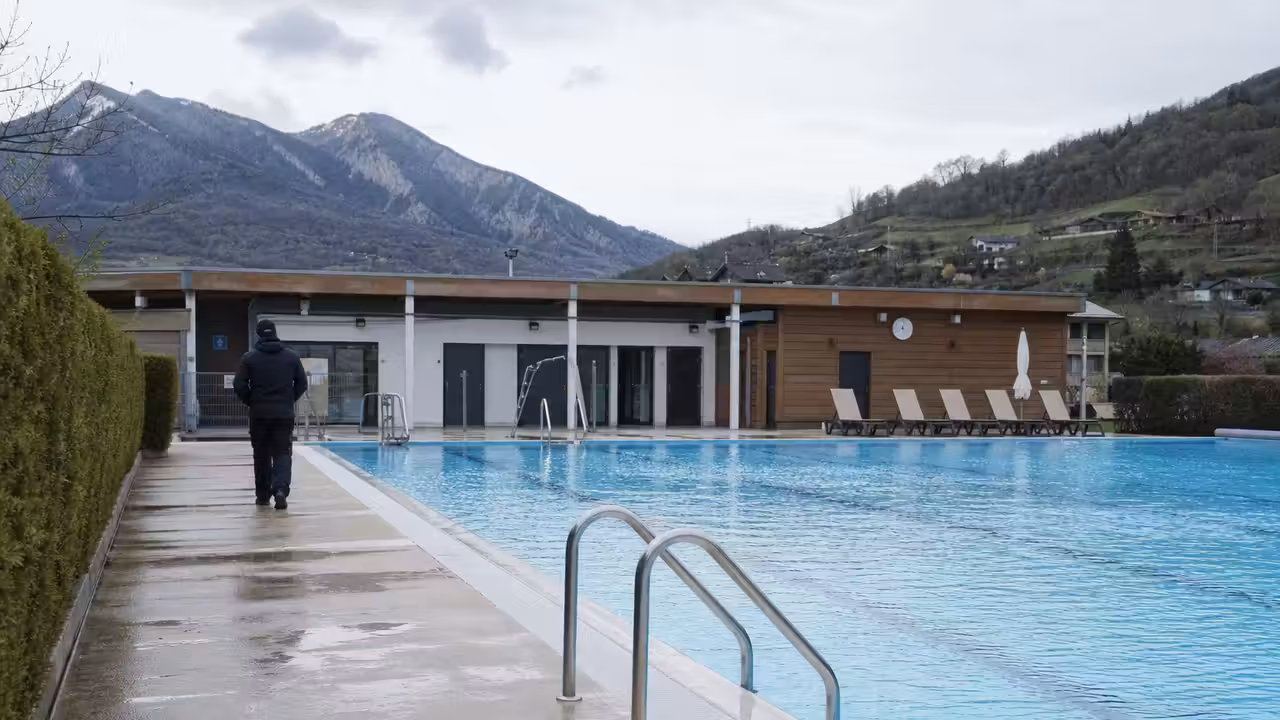 Bassin extérieur d’une piscine municipale préparé pour la saison, avec vestiaires rénovés en arrière-plan