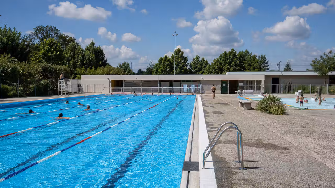 Bassin extérieur de piscine municipale animé en été, avec lignes d’eau et zone de détente surveillée