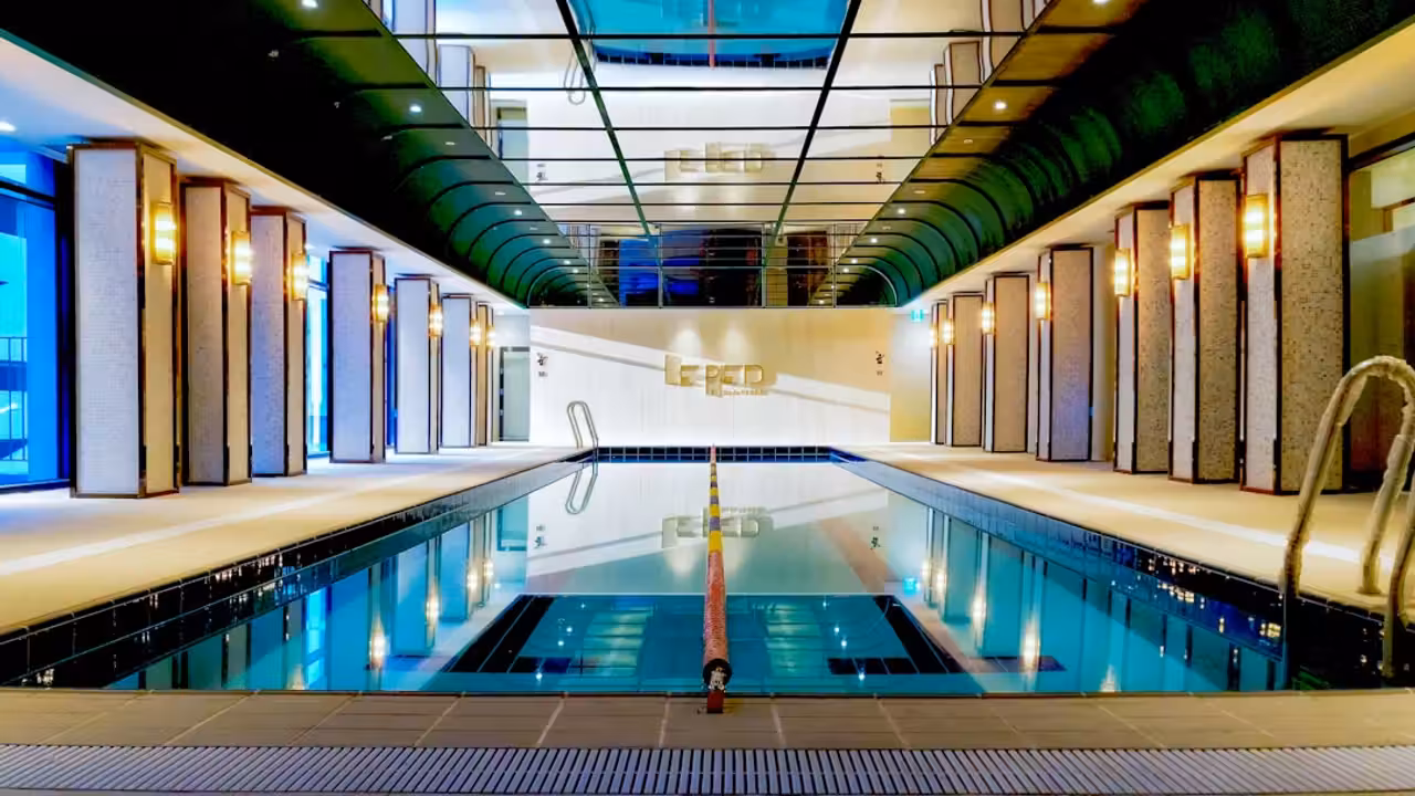 Piscine privée couverte au crépuscule, avec pompe à chaleur et végétaux sobres en bord de terrasse