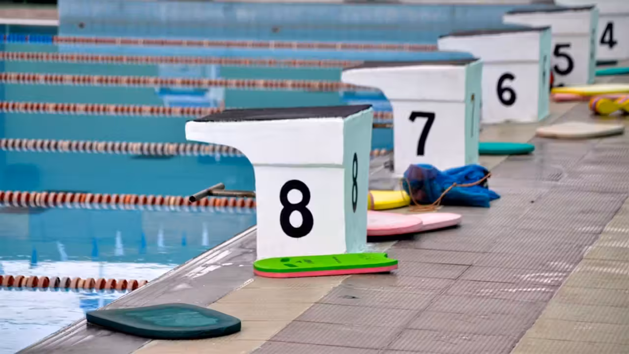 Nageuse adulte accompagnée par un maître-nageur dans un bassin couvert lumineux lors d’un cours de natation