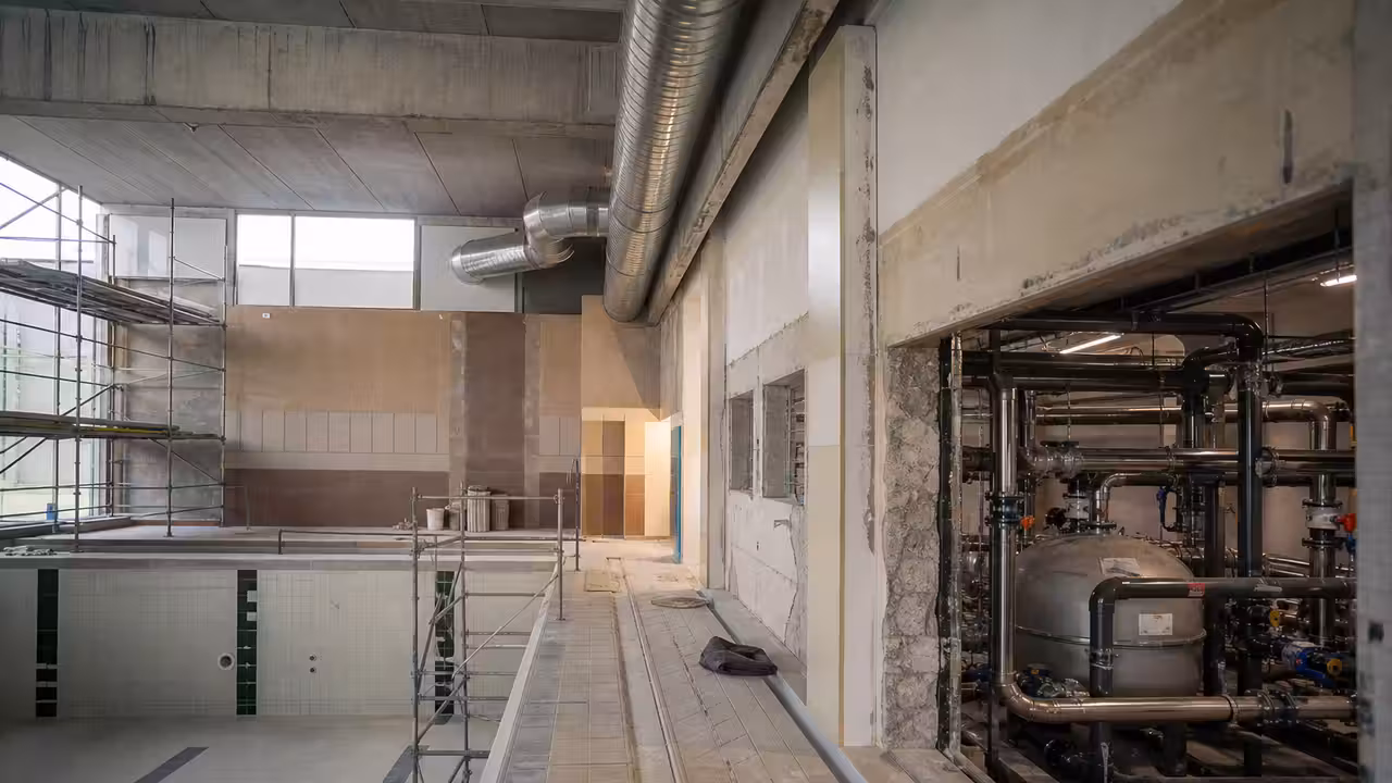 Bassin intérieur d’une piscine municipale en rénovation avec réseaux techniques et lumière naturelle