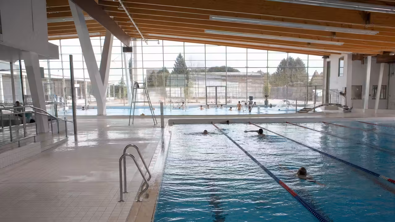 Bassin couvert de 25 mètres dans un centre aquatique municipal, avec lignes d’eau et lumière naturelle
