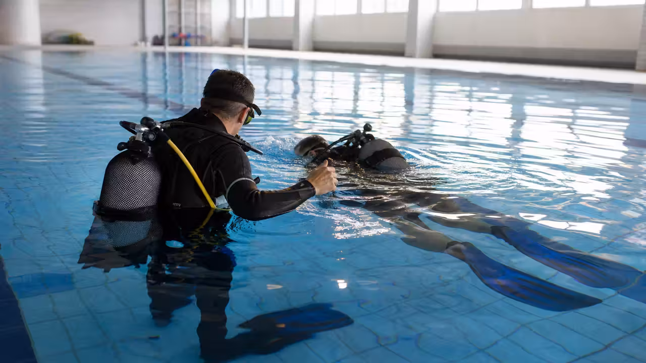 Plongeur débutant équipé d’un détendeur, encadré dans le bassin calme d’une piscine municipale