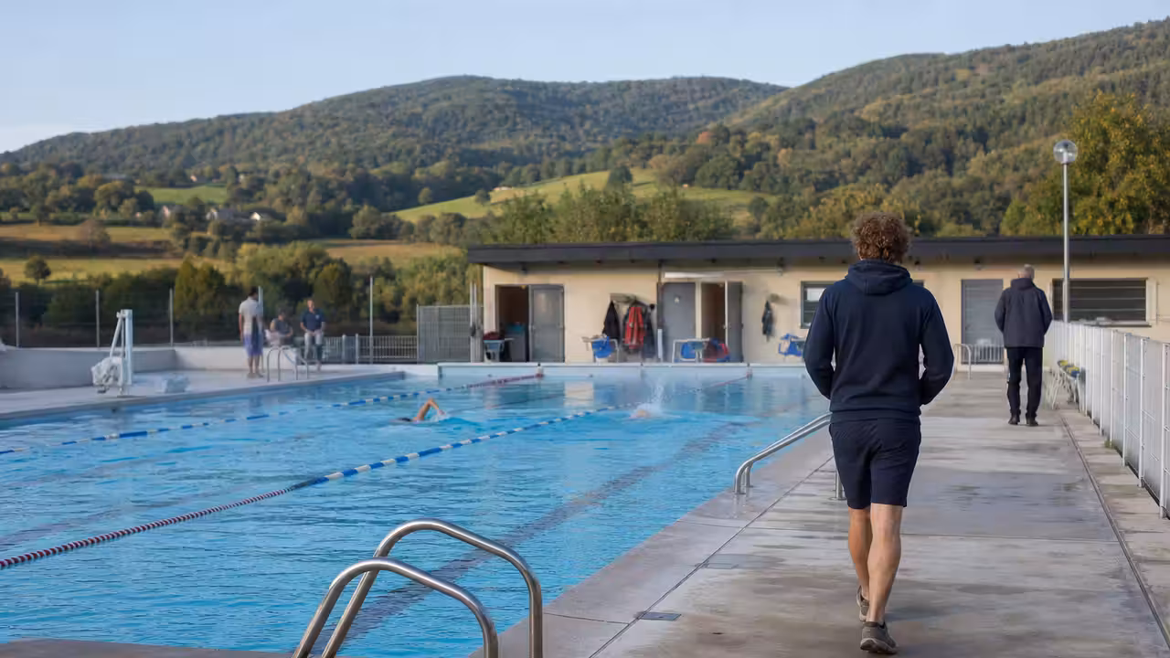 Bassin extérieur de piscine publique de proximité entouré de collines, préparé pour une journée sportive locale