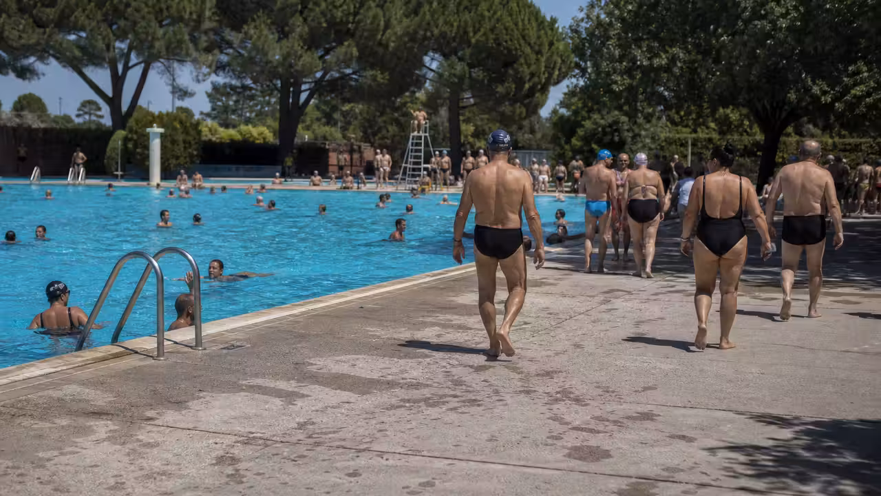 Bassin extérieur municipal très fréquenté lors d’une chaude journée d’été, surveillé depuis le bord
