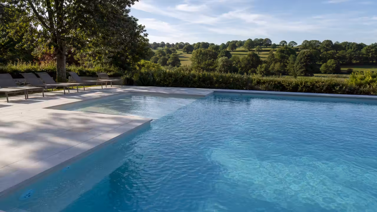 Piscine extérieure de camping entourée de végétation, avec plage antidérapante et espaces de détente