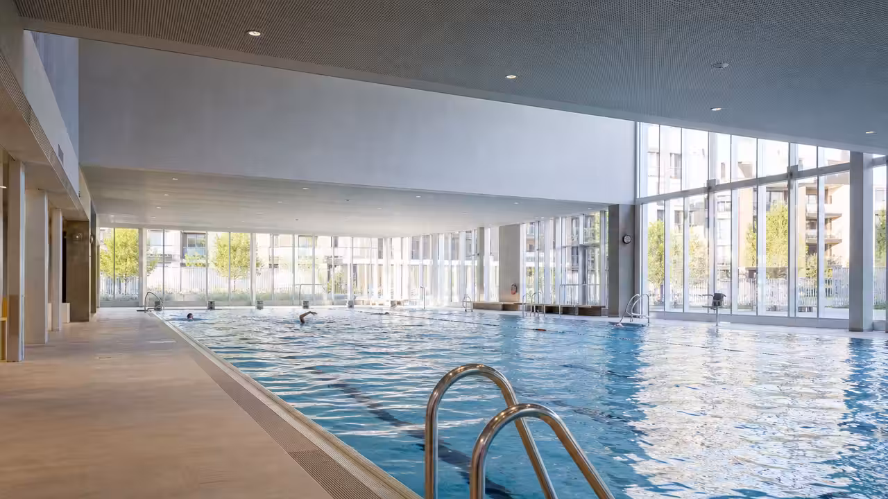Vue intérieure d’un centre aquatique rénové avec bassin de nage, plages antidérapantes et lumière naturelle