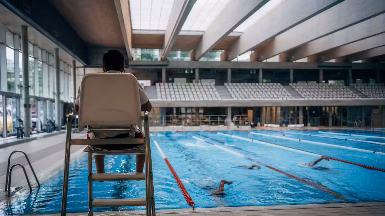 Hall lumineux d’un grand centre aquatique avec bassins sportifs, gradins et lignes d’eau calmes