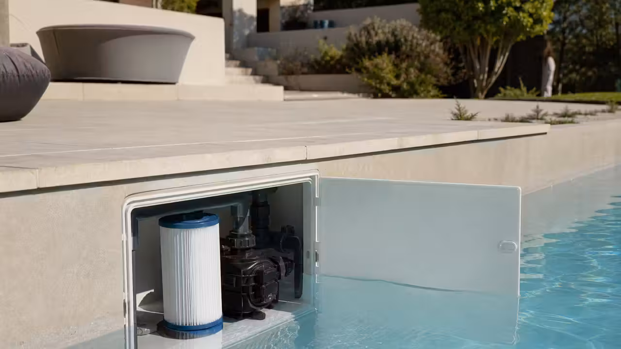 Bloc de filtration intégré dans la paroi d’une piscine, avec eau claire et terrasse minérale
