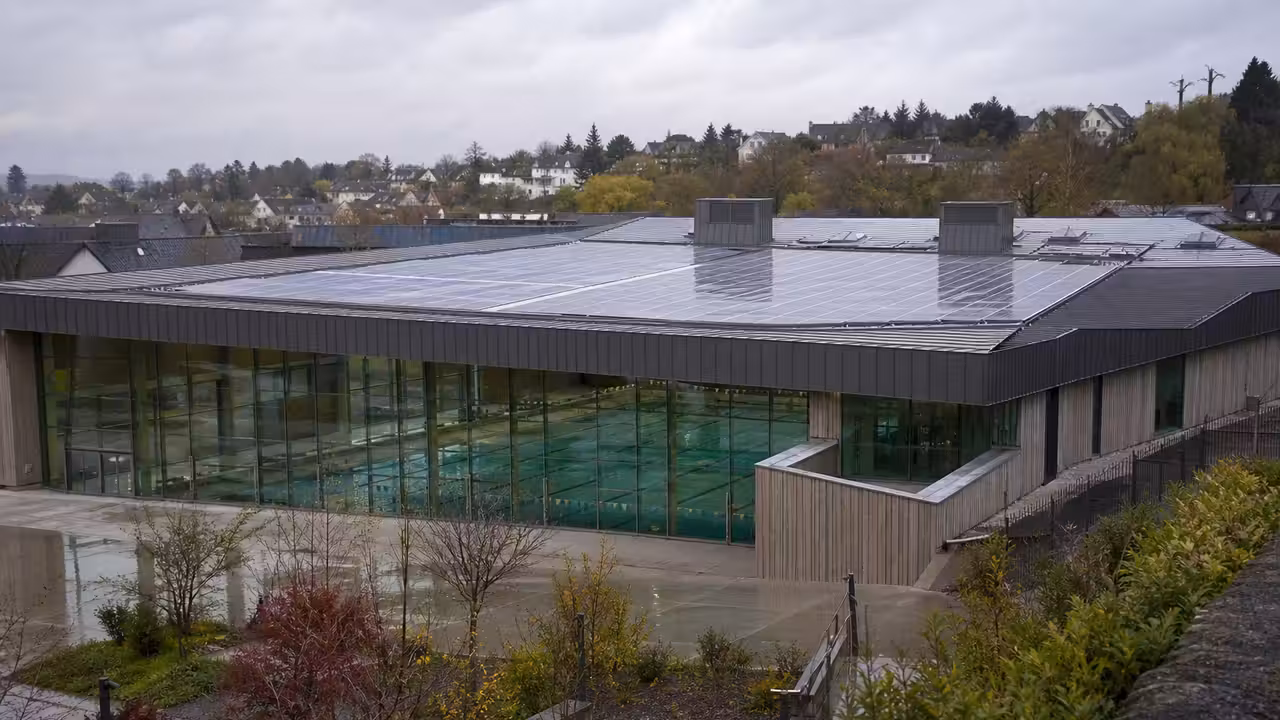 Toiture d’une piscine municipale équipée de panneaux solaires, avec bassin couvert visible en contrebas
