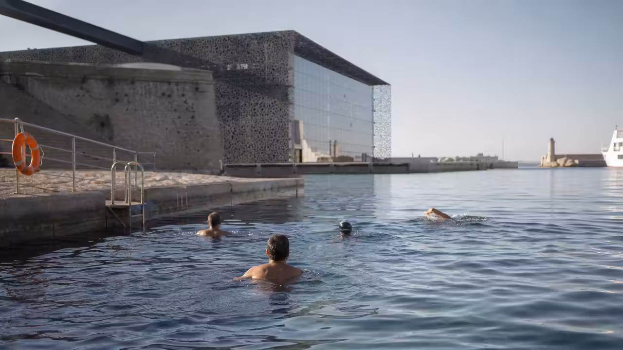 Bassin maritime près du Mucem à Marseille, avec nageurs observant l’eau et les quais au premier plan