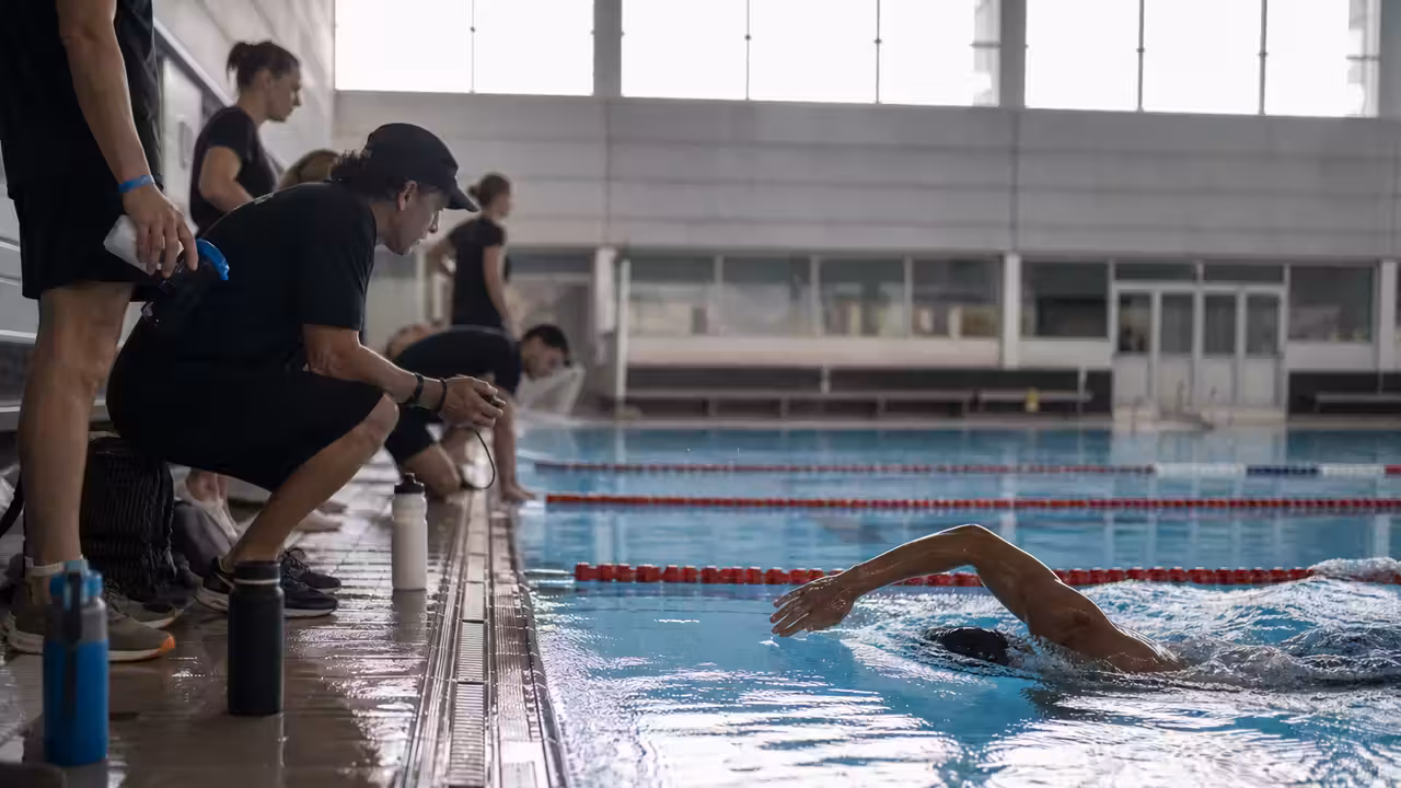 Nageur d’endurance en couloir de piscine observé par une équipe lors d’un entraînement prolongé
