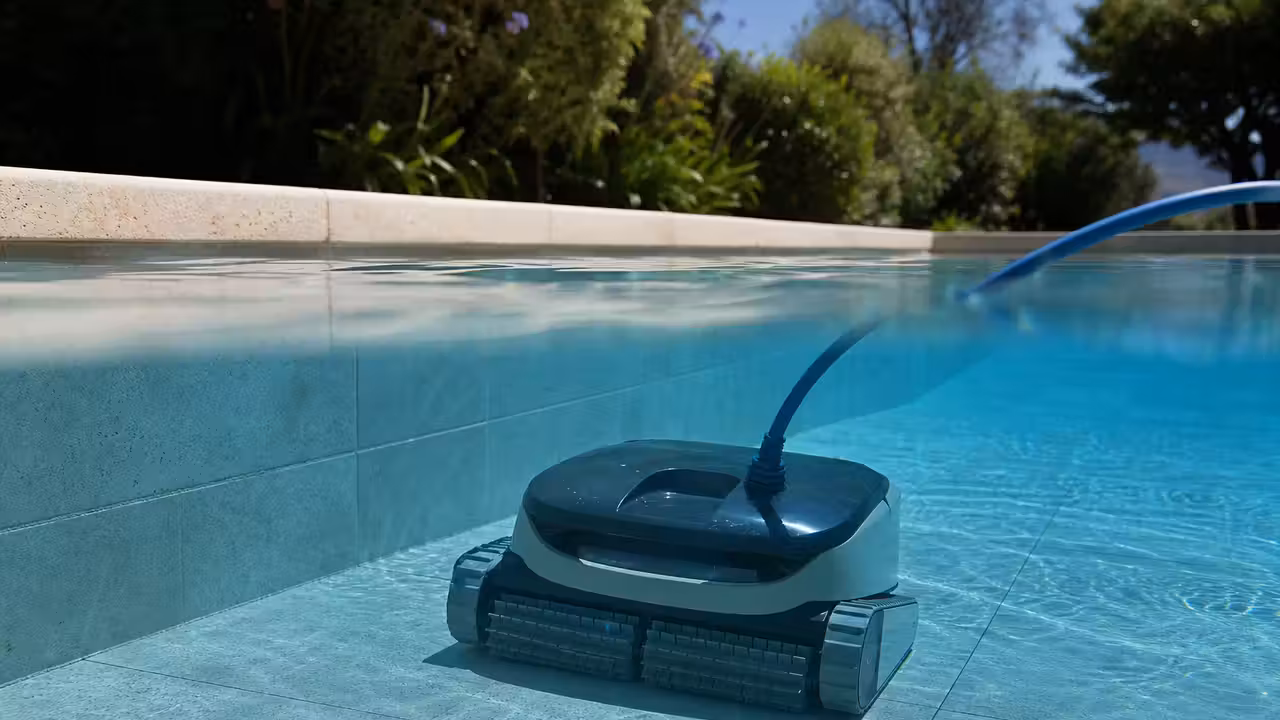 Robot électrique nettoyant le fond carrelé d'une piscine privée aux reflets bleus, sans baigneurs