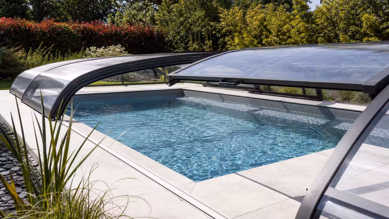 Abri télescopique bas en aluminium et panneaux transparents installé sur une piscine rectangulaire contemporaine