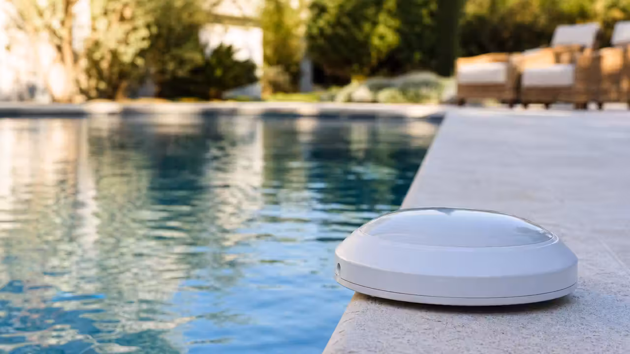 Alarme par immersion fixée sur une margelle au bord d’une piscine privée avec terrasse dégagée