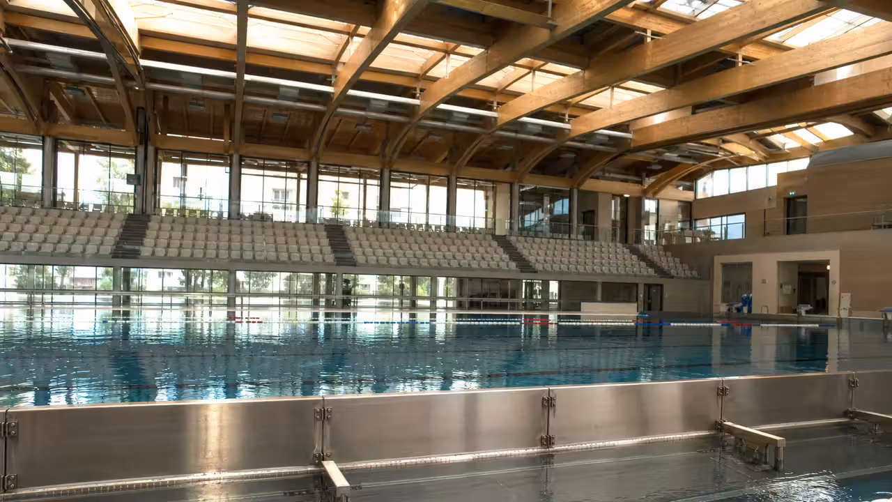 Bassin de compétition en inox avec lignes d’eau et séparations mobiles dans un centre aquatique moderne