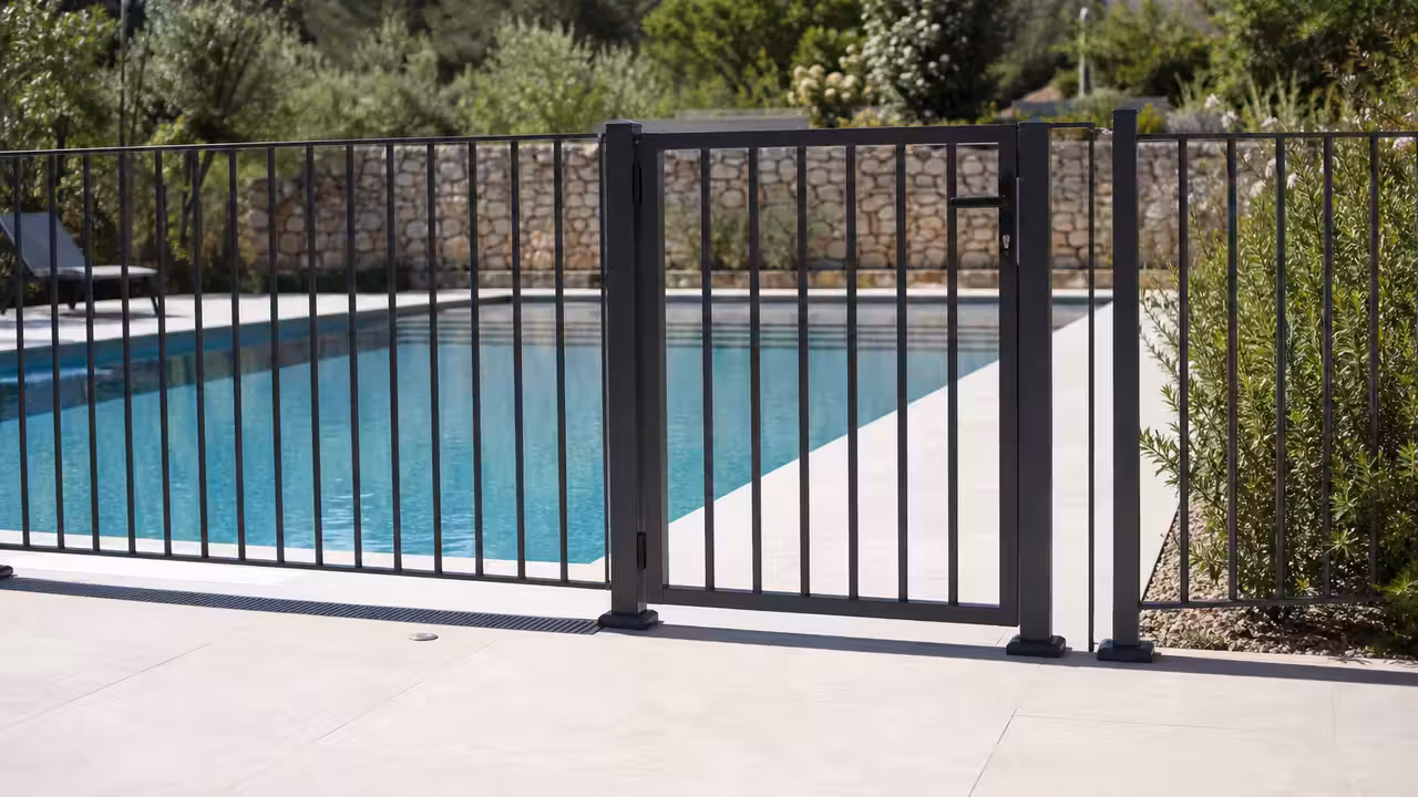 Barrière de piscine en aluminium thermolaqué avec portillon fermé autour d’un bassin familial extérieur