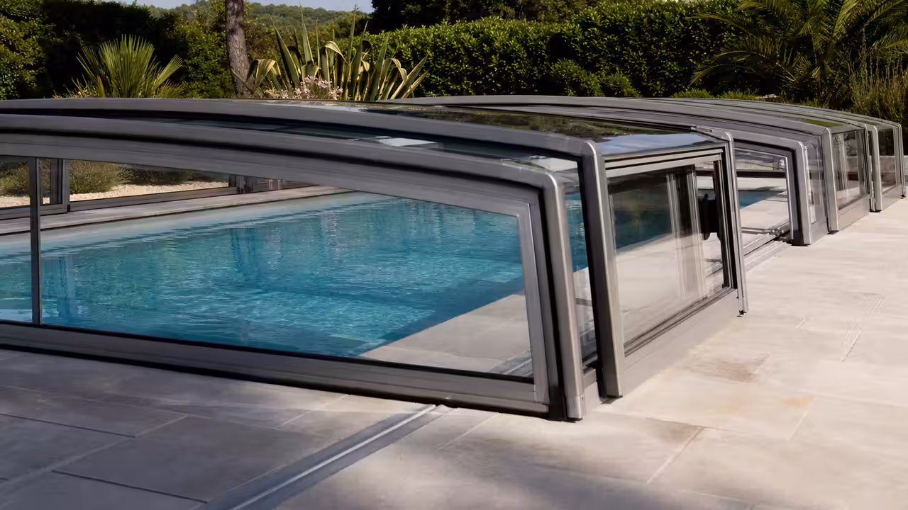 Abri de piscine bas télescopique en aluminium et polycarbonate couvrant un bassin rectangulaire