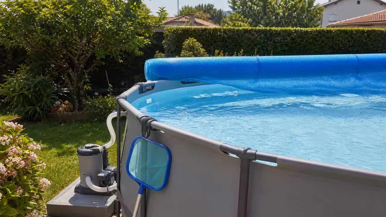 Piscine hors-sol tubulaire équipée d’une pompe de filtration et d’une bâche solaire dans un jardin familial